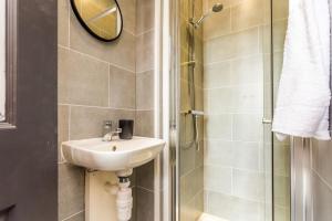 uma casa de banho com um lavatório e um chuveiro com um espelho. em Room 04 - Sandhaven Rooms Triple em South Shields