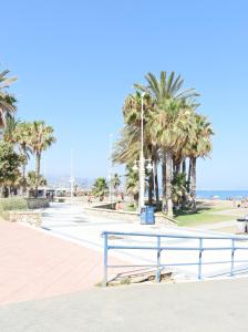 un banco azul junto a la playa con palmeras en Amalia's Home: Luminoso apartamento muy cerca de la playa, en Málaga