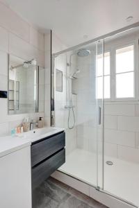 La salle de bains blanche est pourvue d'une douche et d'un lavabo. dans l'établissement 341 Suite Modern Art - Superb Apartment in Paris, à Suresnes