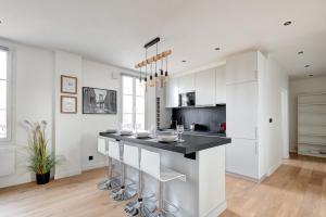 une cuisine avec des placards blancs et un comptoir noir dans l'établissement 341 Suite Modern Art - Superb Apartment in Paris, à Suresnes