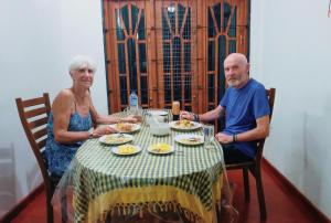un hombre y una mujer sentados en una mesa comiendo comida en Kande Gedara Resort (කන්දෙ ගෙදර) en Monaragala