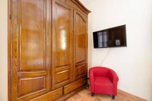 a red chair sitting next to a large wooden cabinet at Agrifoglio B&B con giardino in Aritzo