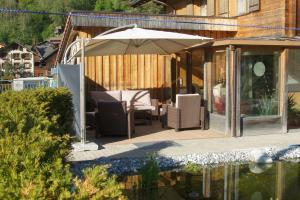 un patio con sombrilla y sillas junto a una piscina en Beat & Ursula's Guest House en Jenaz