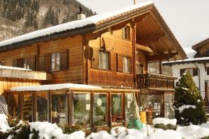 a large wooden house with snow on it at Beat & Ursula's Guest House in Jenaz
