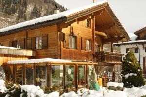 una grande casa in legno con la neve di Beat & Ursula's Guest House a Jenaz