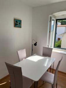 una mesa y sillas blancas en una habitación con ventana en Villa Adria en Brist
