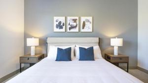 una camera da letto con un letto con cuscini blu e 2 lampade di Landing - Modern Apartment with Amazing Amenities (ID9024X45) a Spring Hill