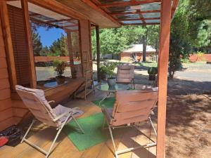 una veranda riparata con sedie e tavolo di Cabañas Condominio El Bosque a Pucón
