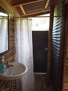 baño con lavabo y puerta de ducha en tukamping, en Minca