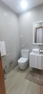 a white bathroom with a toilet and a sink at Ondas Relax House in Praia