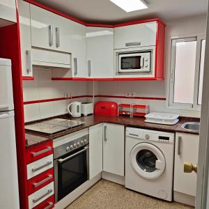 プエルト・デ・サグントにあるRelaxed Space in the beachのキッチン(赤いキャビネット、洗濯機、乾燥機付)