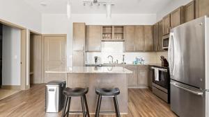 - une cuisine avec un réfrigérateur en acier inoxydable et deux tabourets dans l'établissement Landing - Modern Apartment with Amazing Amenities (ID7923X25), à Spring Hill