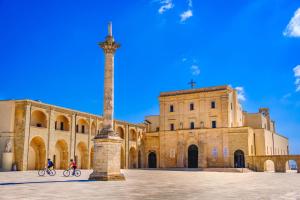 due persone in bicicletta di fronte a un edificio di Stella Marina a Leuca