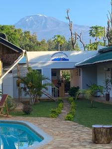 una casa con piscina y una montaña en el fondo en Karanga River Lodge, en Moshi
