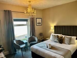 a bedroom with a bed and a chandelier and a window at Hotel No5 Beach front with Free Private Car Park in Llandudno