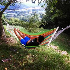 a person laying in a hammock in a field at Casa de colònies La Cadamont in Sant Joan les Fonts