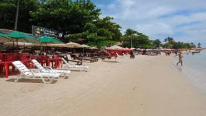 a beach with chairs and umbrellas and people on it at Ytamãní ll apartamentos in Santa Cruz Cabrália