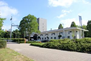 un edificio blanco con una torre en el fondo en Bastion Hotel Roosendaal en Roosendaal