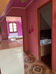 baño con paredes rosas, bañera y espejo en BRC Hostel & Car Rent Budapest en Budapest