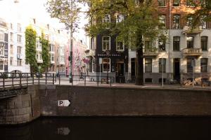 un canale in una città con edifici e case di BackStage Hotel ad Amsterdam