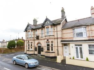 a blue car parked in front of a brick house at The Keyberry Hotel in Newton Abbot