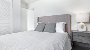 a white bedroom with a bed and a lamp at Landing - Modern Apartment with Amazing Amenities (ID9305X02) in Ballwin
