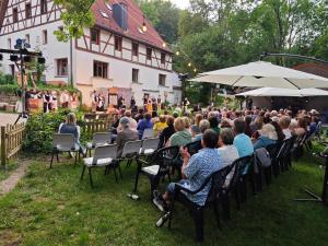 Une foule de personnes assises sur des chaises pour assister à un concert dans l'établissement Appartment Mühlberg Obermühle, à Kirchensittenbach
