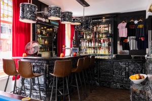 een bar met een zwarte bar en krukken bij BackStage Hotel in Amsterdam