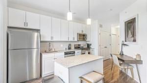 cocina con armarios blancos y nevera de acero inoxidable en Landing - Modern Apartment with Amazing Amenities (ID8724X56), en Lombard
