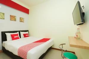 - une chambre avec un lit doté d'oreillers rouges et une télévision dans l'établissement SUPER OYO Flagship 3688 Pot Art, à Surabaya