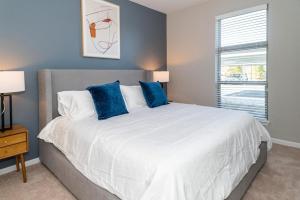 a bedroom with a large white bed with blue pillows at Landing - Modern Apartment with Amazing Amenities (ID4378) in Auburn Hills