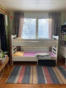 1 Schlafzimmer mit 2 Etagenbetten und einem Fenster in der Unterkunft Old Cozy Wood House in Rovaniemi