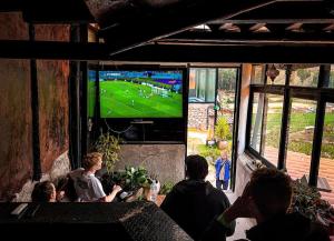 een groep mensen die een voetbalwedstrijd op televisie kijken bij Wolf Totem Industrial Chic Studio in Pisac