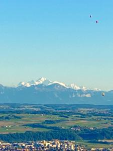 twee luchtballonnen die over een stad vliegen met sneeuw bedekte bergen bij Tévenon Vue Panoramique Alpes-Lac in Grandevent