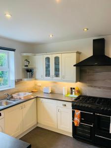 a kitchen with white cabinets and a black stove top oven at Chic 5 Bedroom House with Private Parking & Garden in Bristol +20 photos