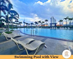 a swimming pool with two white chairs and palm trees at Trion Kuala Lumpur Near Sunway Velocity KLCC TRX Bukit Bintang in Kuala Lumpur