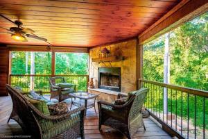a screened in porch with chairs and a fireplace at Iron Horse Lodge sleeps 18, Games, Fire Pit, Hot Tub, EV, more in Broken Bow