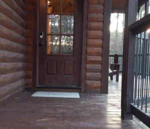 a wooden door on a house with a porch at Iron Horse Lodge sleeps 18, Games, Fire Pit, Hot Tub, EV, more in Broken Bow