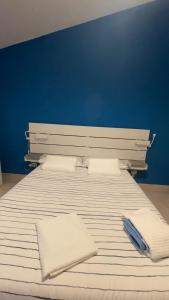 a white bed with two pillows and a blue wall at Itiseasy Cuglieri Luxury Apartments in Cuglieri