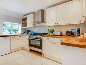 2 Bed in Horsted Keynes 60405 في Horsted Keynes: مطبخ بدولاب بيضاء وفرن علوي موقد