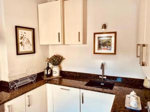 a kitchen with white cabinets and a sink at Pass the Keys Cobblers Rest Luxury Elegance & Central Location in Bakewell