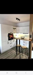 a kitchen with white cabinets and a table and two stools at Apartament na Skrzypka in Cieszyn