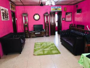 a living room with pink walls and black leather furniture at NICE APARTMENT in Kituoni