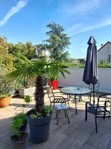 een patio met een tafel, een parasol en stoelen bij Chambre avec mezzanine dans une maison d'artiste in Rueil-Malmaison