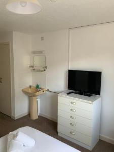 um quarto com uma cama e uma televisão numa cómoda em St Merryn em Carbis Bay