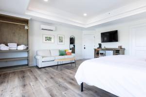 een witte slaapkamer met een wit bed en een bank bij Avamere 206 Inn at Old Beach in Virginia Beach
