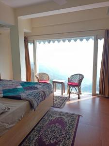 a bedroom with a bed and a large window at Beechwood Holiday Apartments in Mussoorie