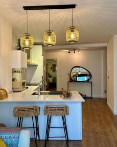 a kitchen with two bar stools and three lights at Sol Mediterráneo Palm City in Elche