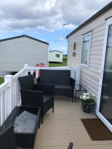 een terras met stoelen en een tafel en een gebouw bij Jules Holiday Caravan in Hartley