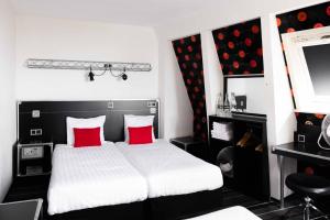 una camera da letto con un letto con cuscini rossi e una televisione di Backstage Hotel Amsterdam ad Amsterdam Altre 47 foto